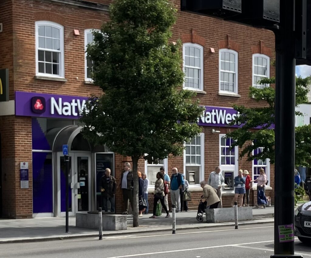 A queue of customers wait for Natwest to open this summer.